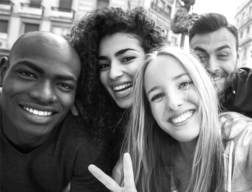 Selfi en blanco y negro de cuatro amigos que sonríen