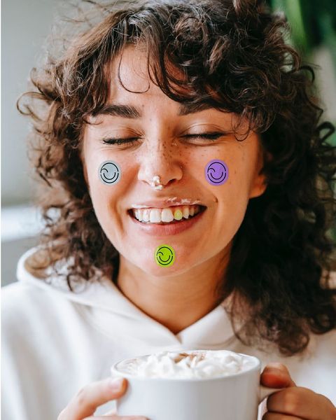 Una mujer ríe con una taza en las manos y stickers del isotipo de Smile Up en la cara